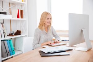 Sacramento Bookkeeping Blonde Woman Working At Her Desk With A Smile SBI 302775680